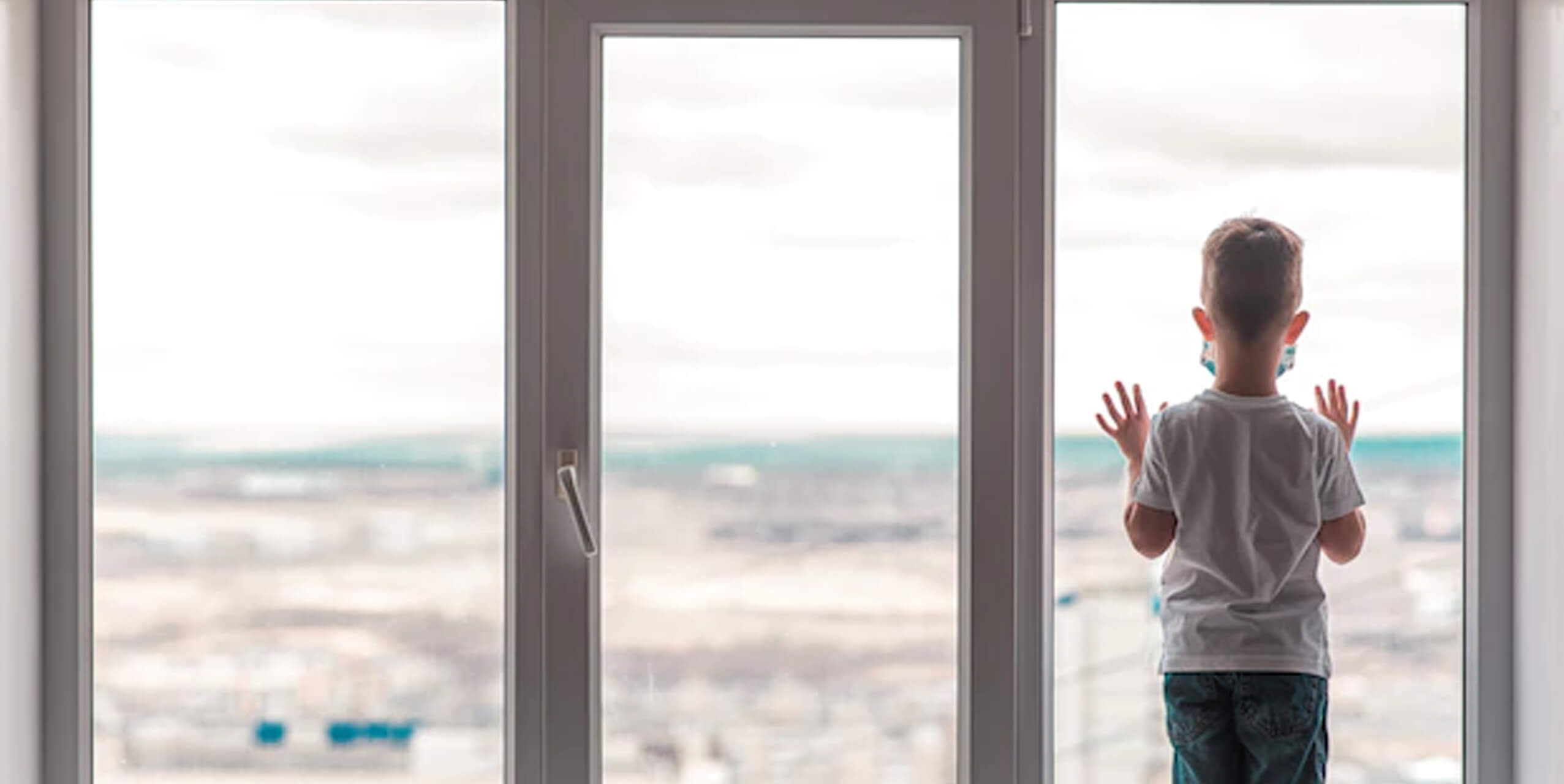 Bambino che guarda dalla finestra in tempi di Pandemia